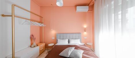 A modern bedroom with a large bed, a bedside table, a mirror, and a hanging light fixture.