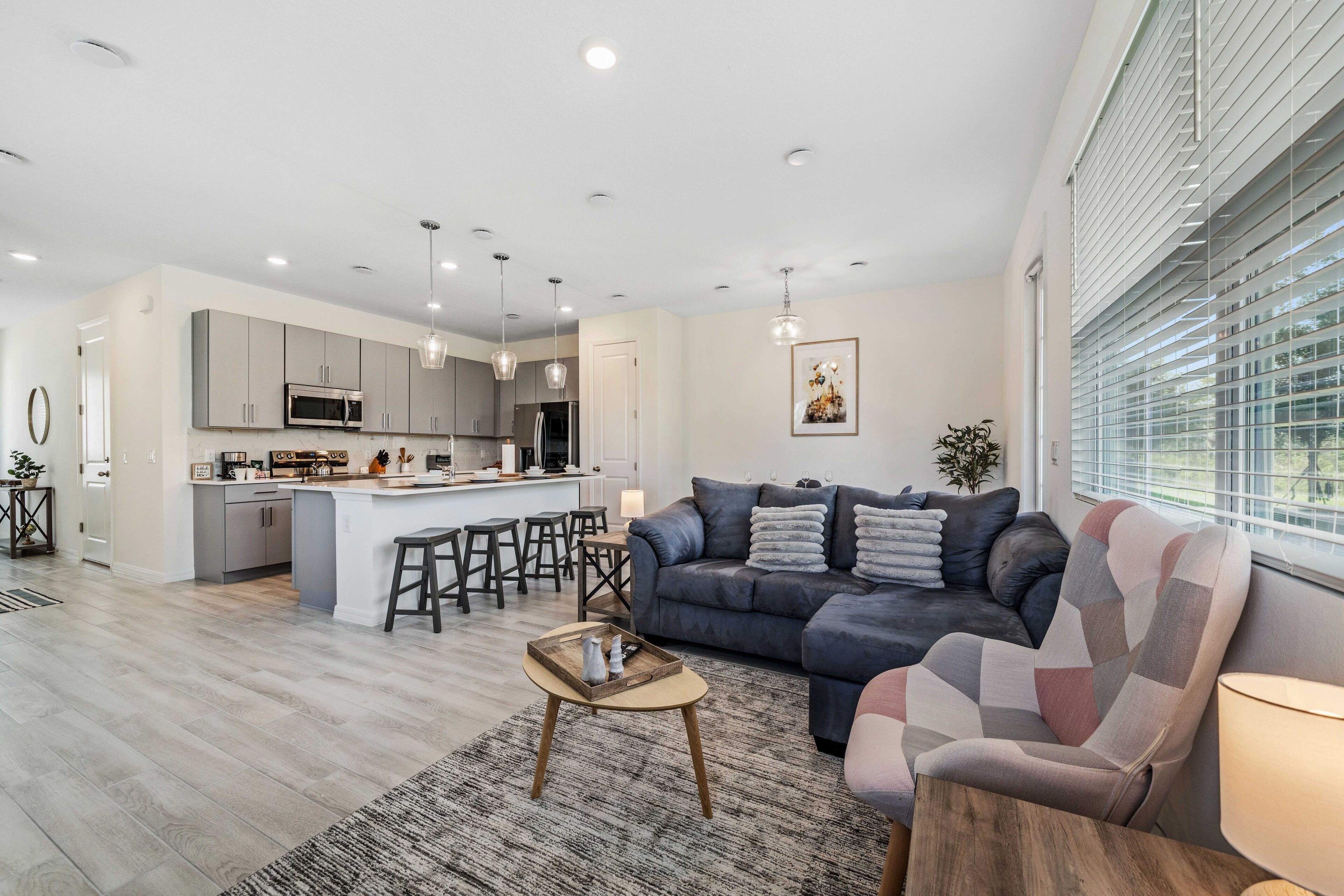 A modern living room with a sofa, coffee table, and a view of the kitchen and dining area.