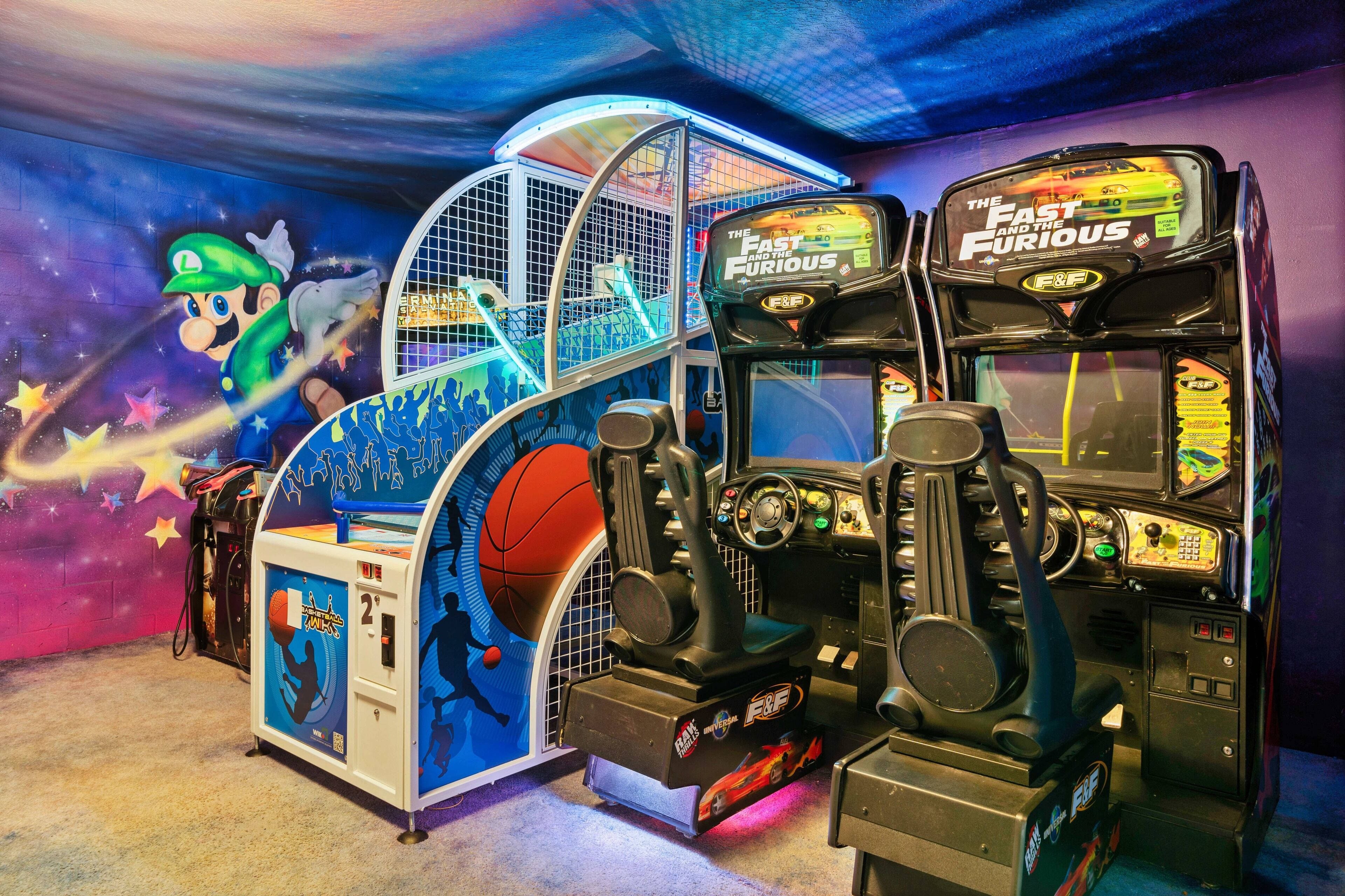A gaming arcade with two racing game machines labeled "The Fast and the Furious."