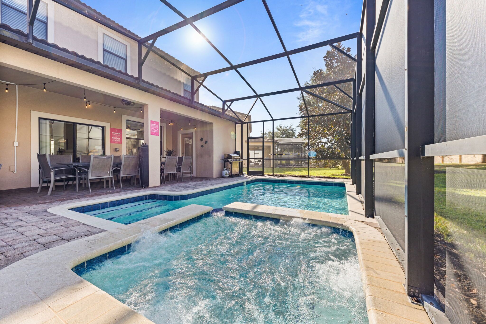 A pool area with a hot tub, outdoor seating, and a covered patio.