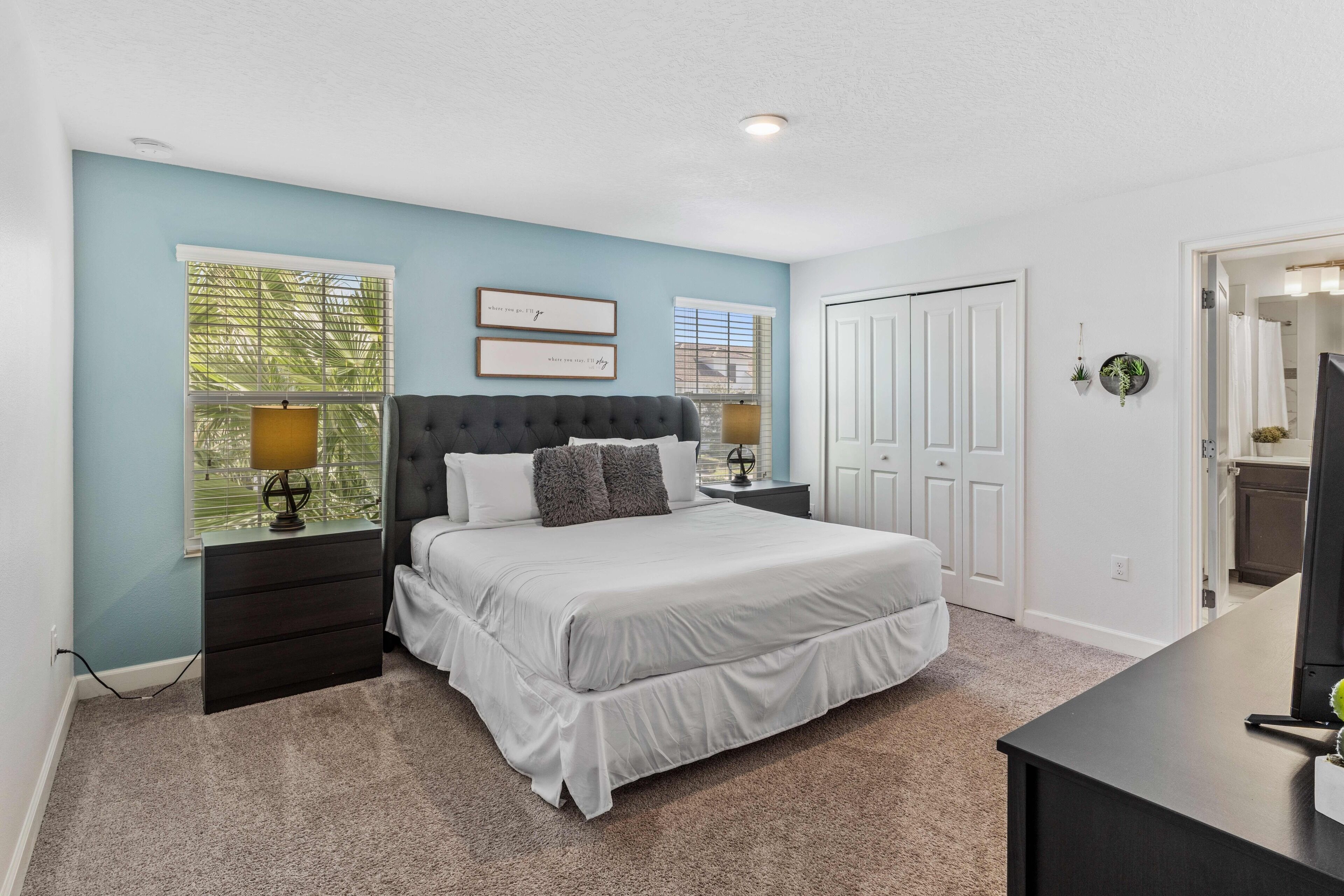 A bedroom with a large bed, two nightstands, a dresser, and a TV.