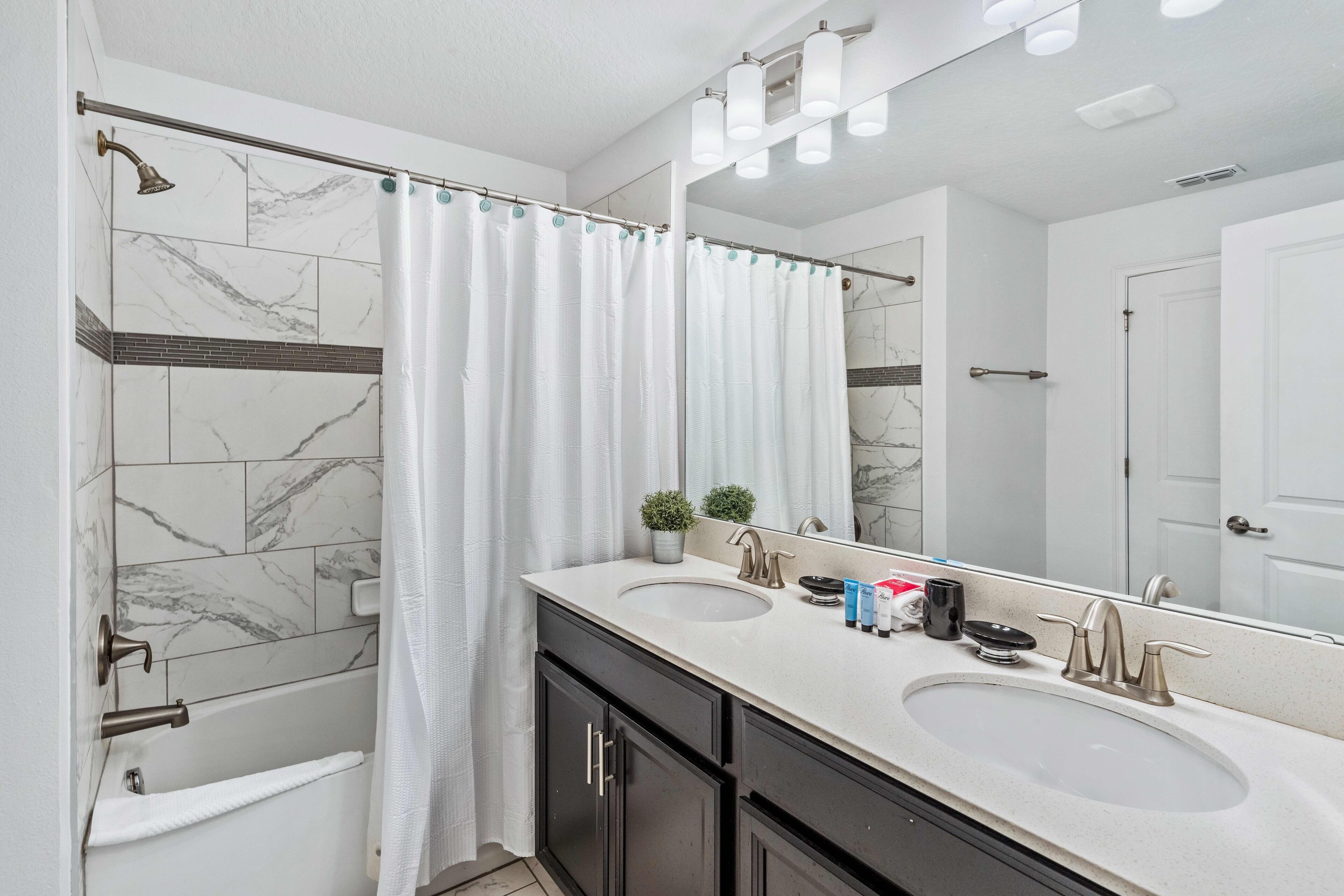 Une salle de bain avec deux lavabos, une douche, un grand miroir et un porte-serviettes.