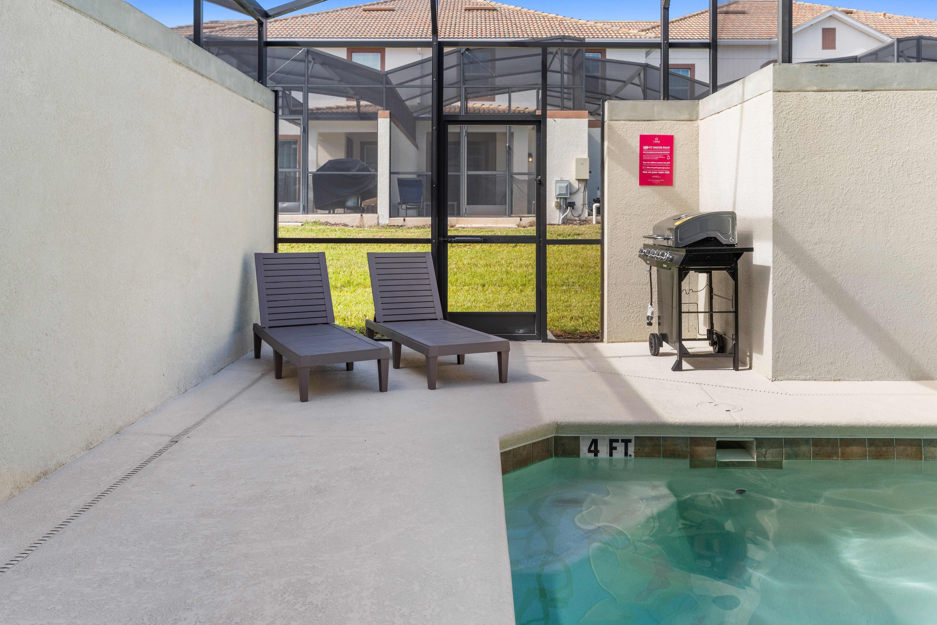 A pool area with lounge chairs, a grill, and a sign indicating a 4 FT depth.
