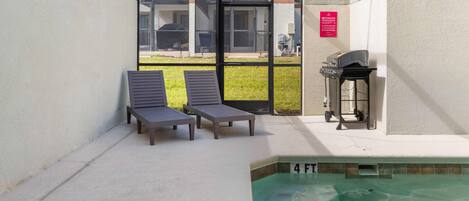 A pool area with lounge chairs, a grill, and a sign indicating a 4 FT depth.
