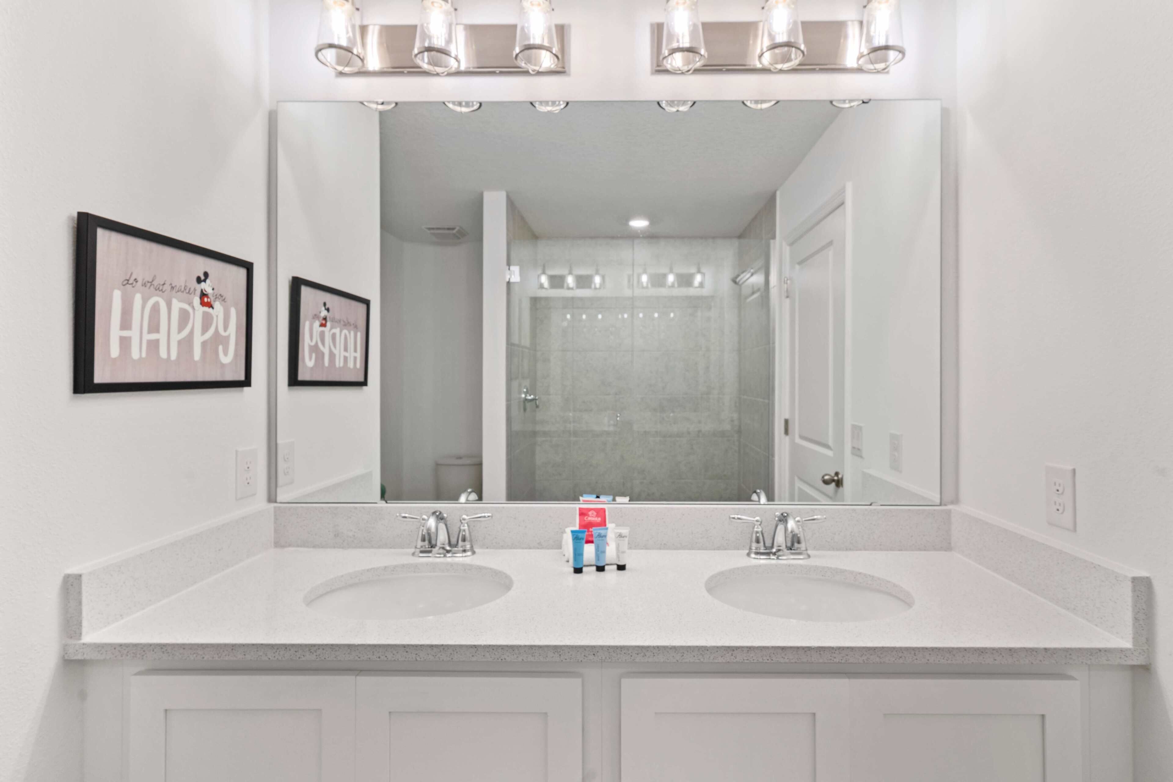 A bathroom with two sinks, a large mirror, and two wall-mounted light fixtures.