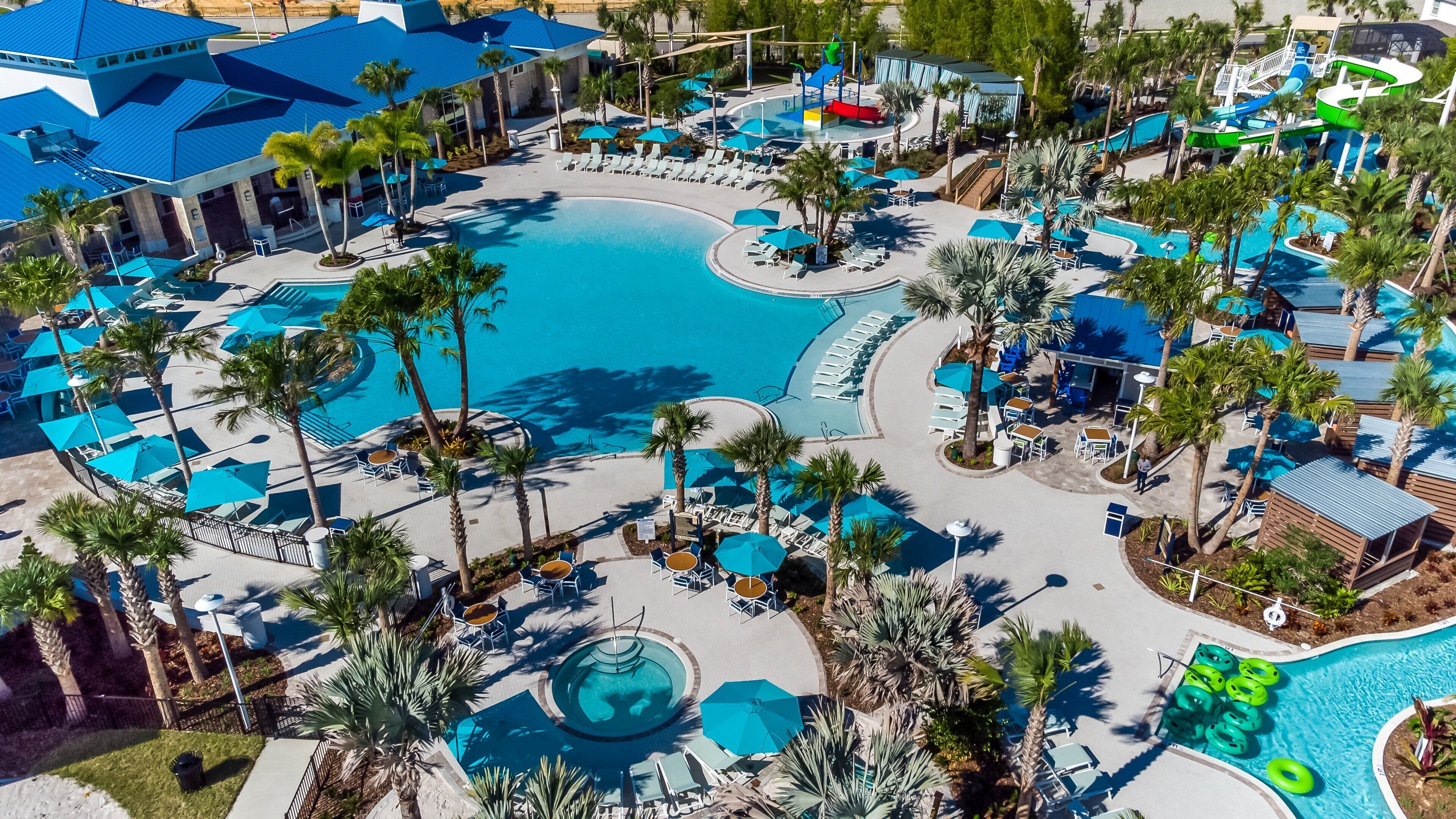 Ein Resort mit mehreren Schwimmbecken, Palmen und Liegestühlen.