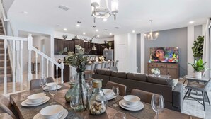 Ein modernes Wohnzimmer mit Essbereich, einer Treppe und einer Küche im Hintergrund.