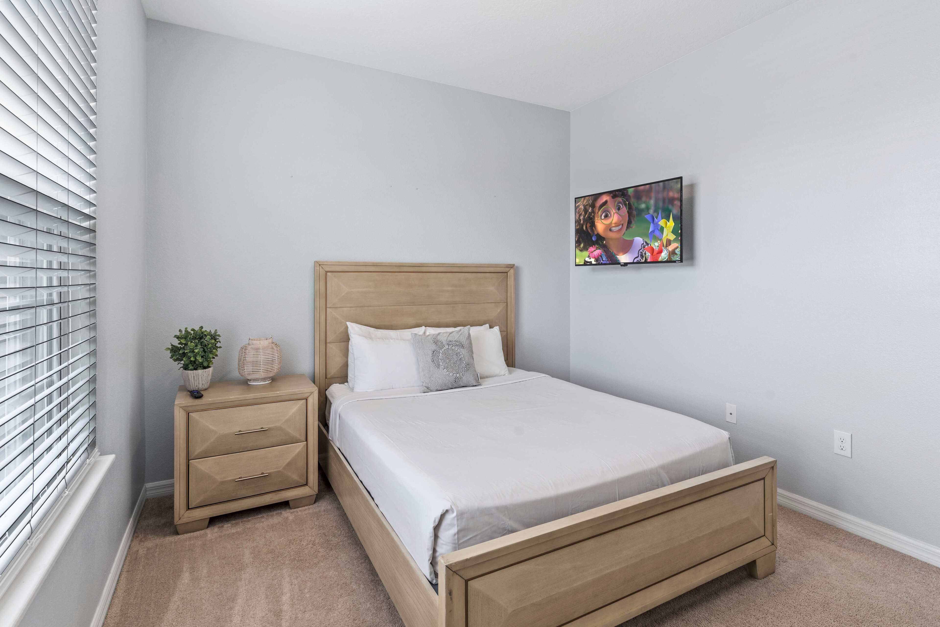 Une chambre à coucher avec un lit, une table de chevet et un téléviseur fixé au mur.