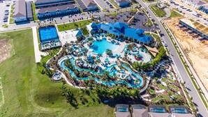 Ein Luftbild eines Resorts mit einem zentralen Schwimmbad, mehreren Gästezimmern und einem Parkplatz.