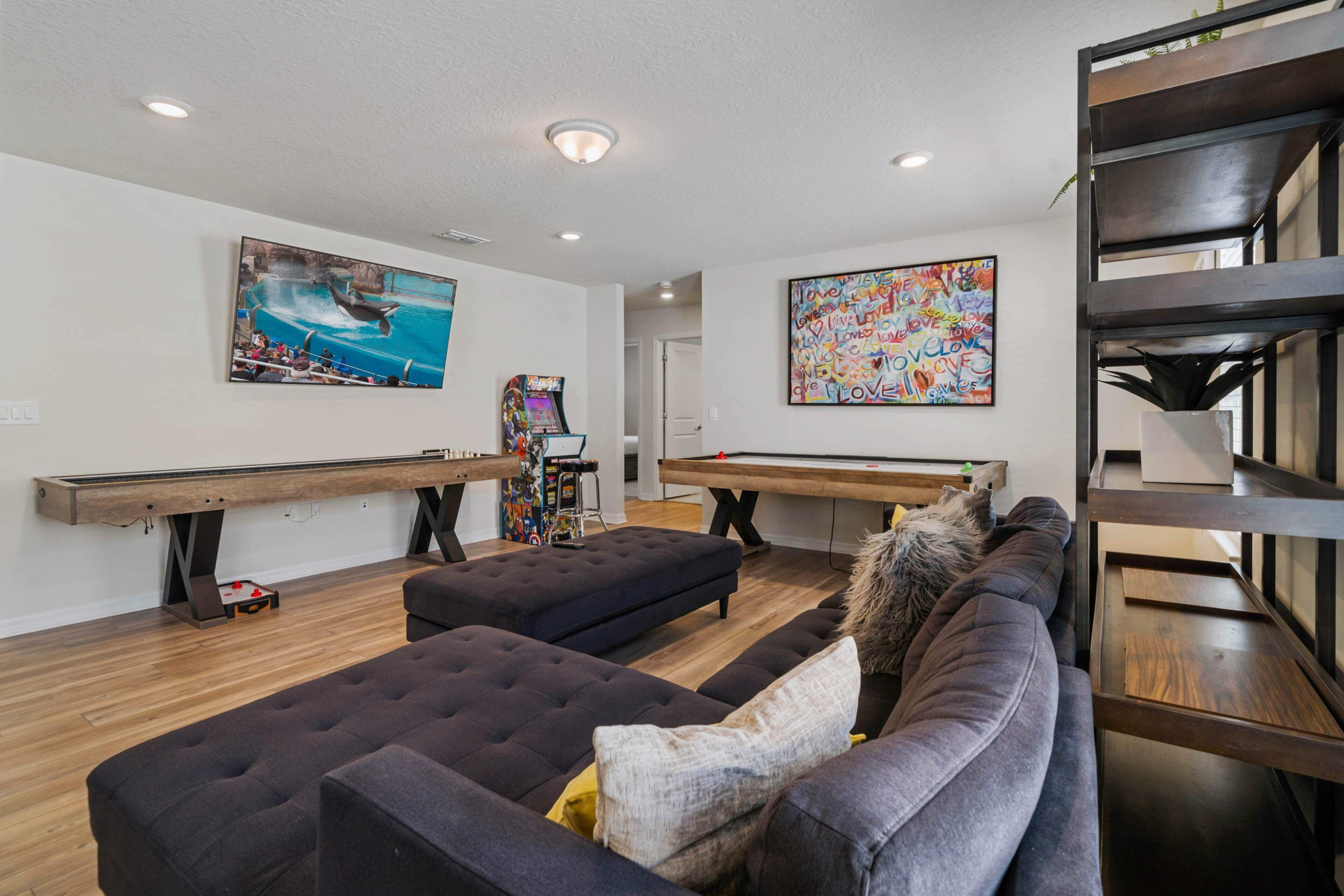 A living room with a pool table, a sofa, and a large painting of a dolphin.