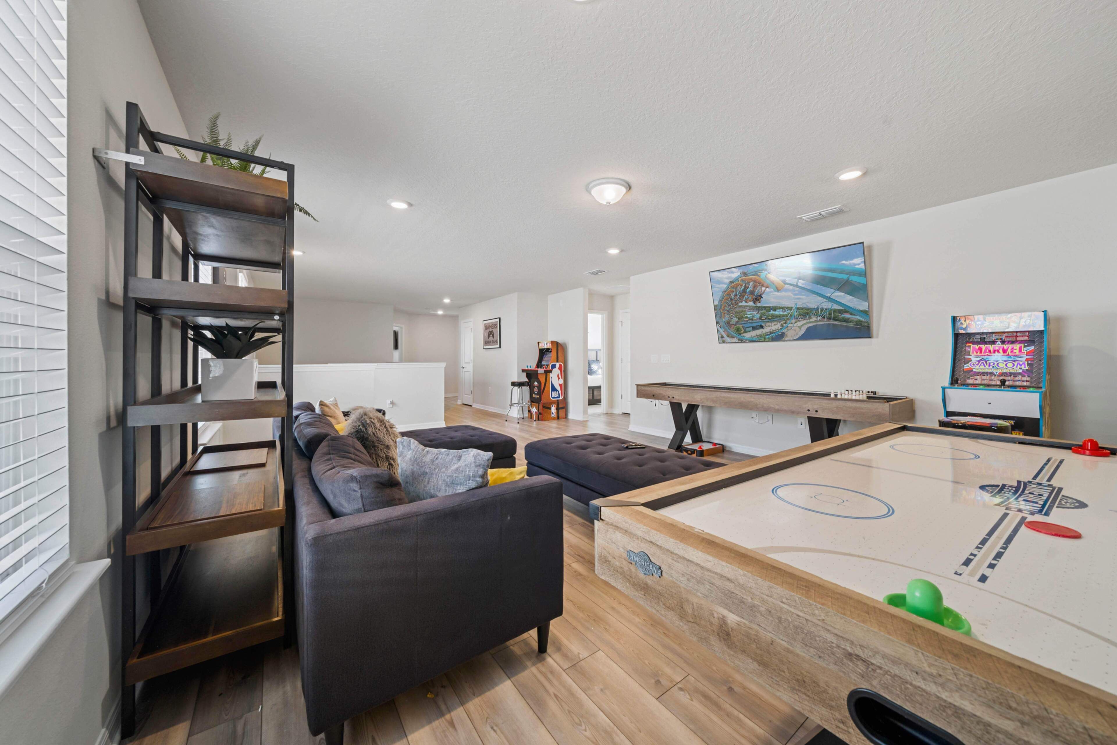 A modern living room with a pool table, a sofa, and a bookshelf.