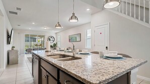 A spacious kitchen with granite countertops, stainless steel appliances, and pendant lighting. - 2211 Lelani Circle (Davenport)