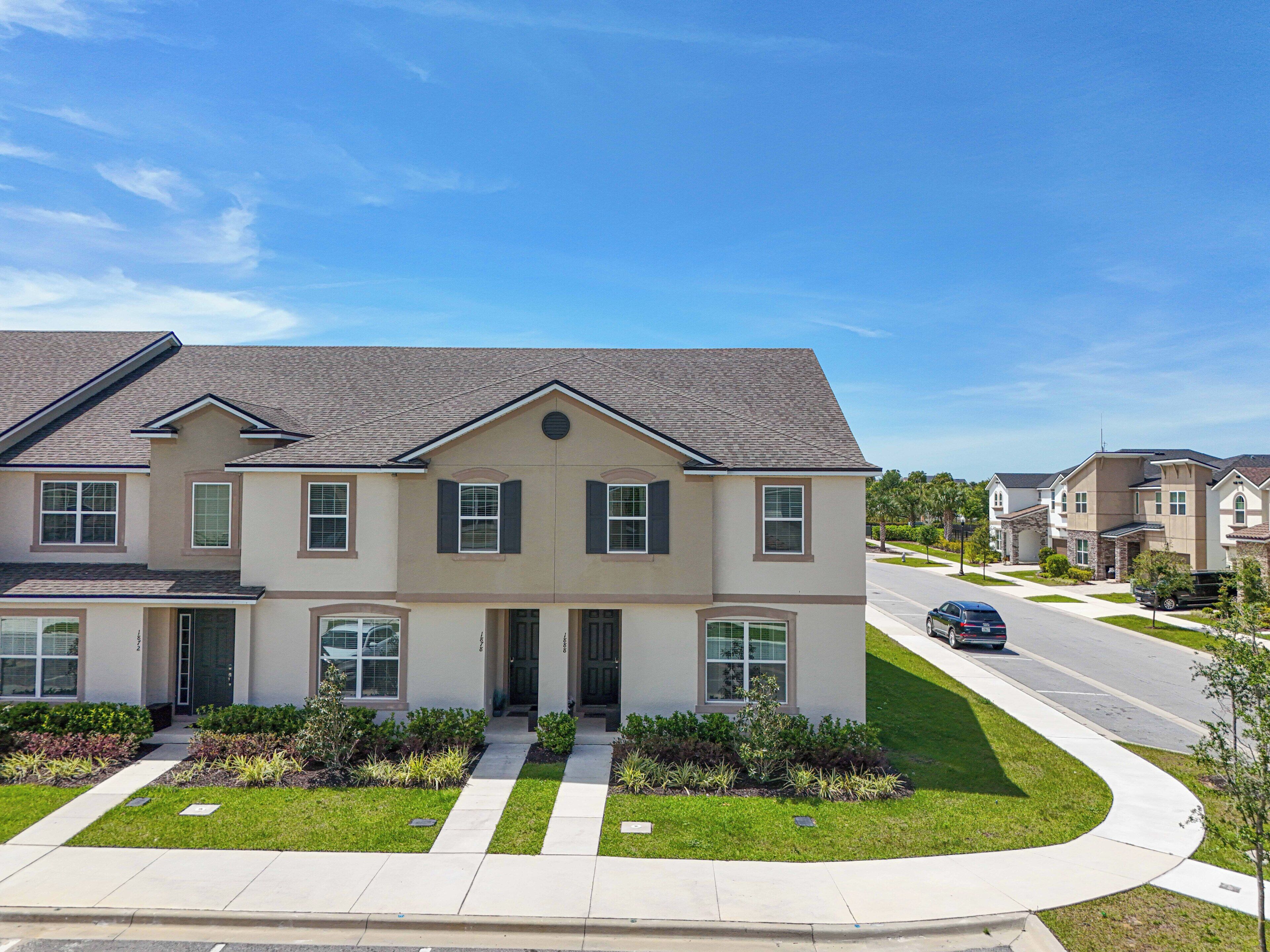 A modern two-story residential building with a symmetrical facade, a central entrance, and a well-maintained lawn.