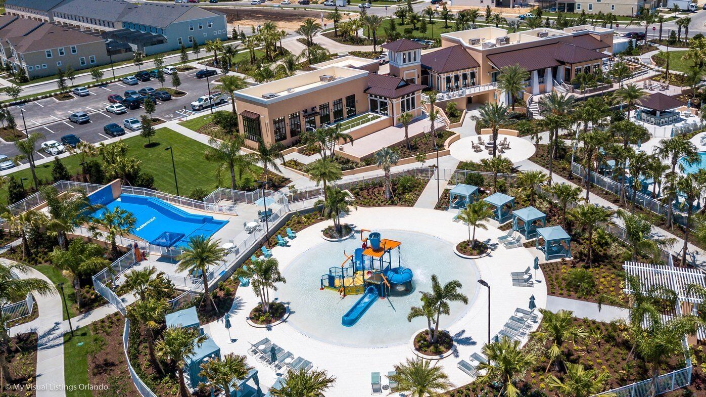 An aerial view of a resort with a central water park, multiple buildings, and a parking area.