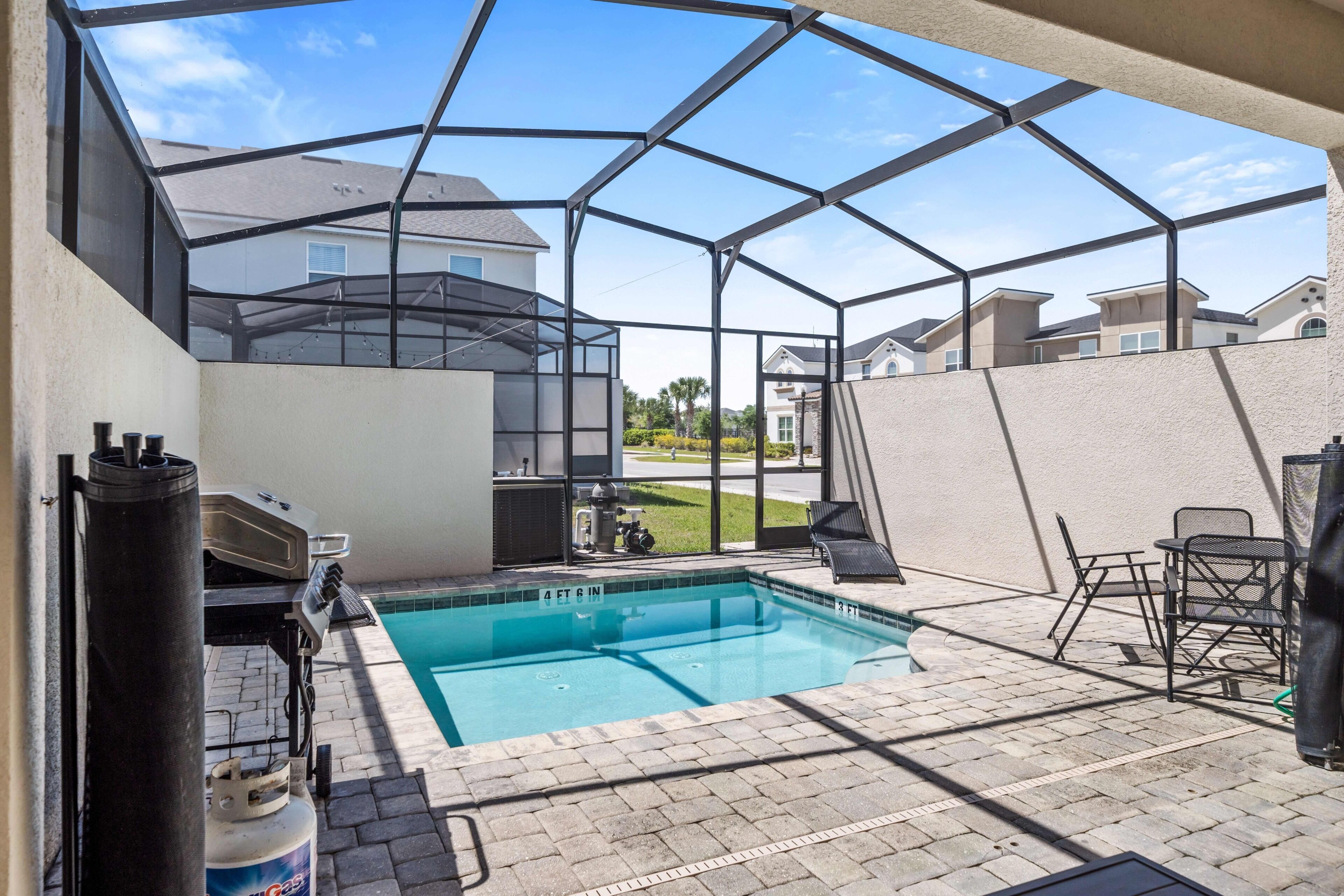 Ein Garten mit Swimmingpool, Terrassenmöbeln und Grillplatz.