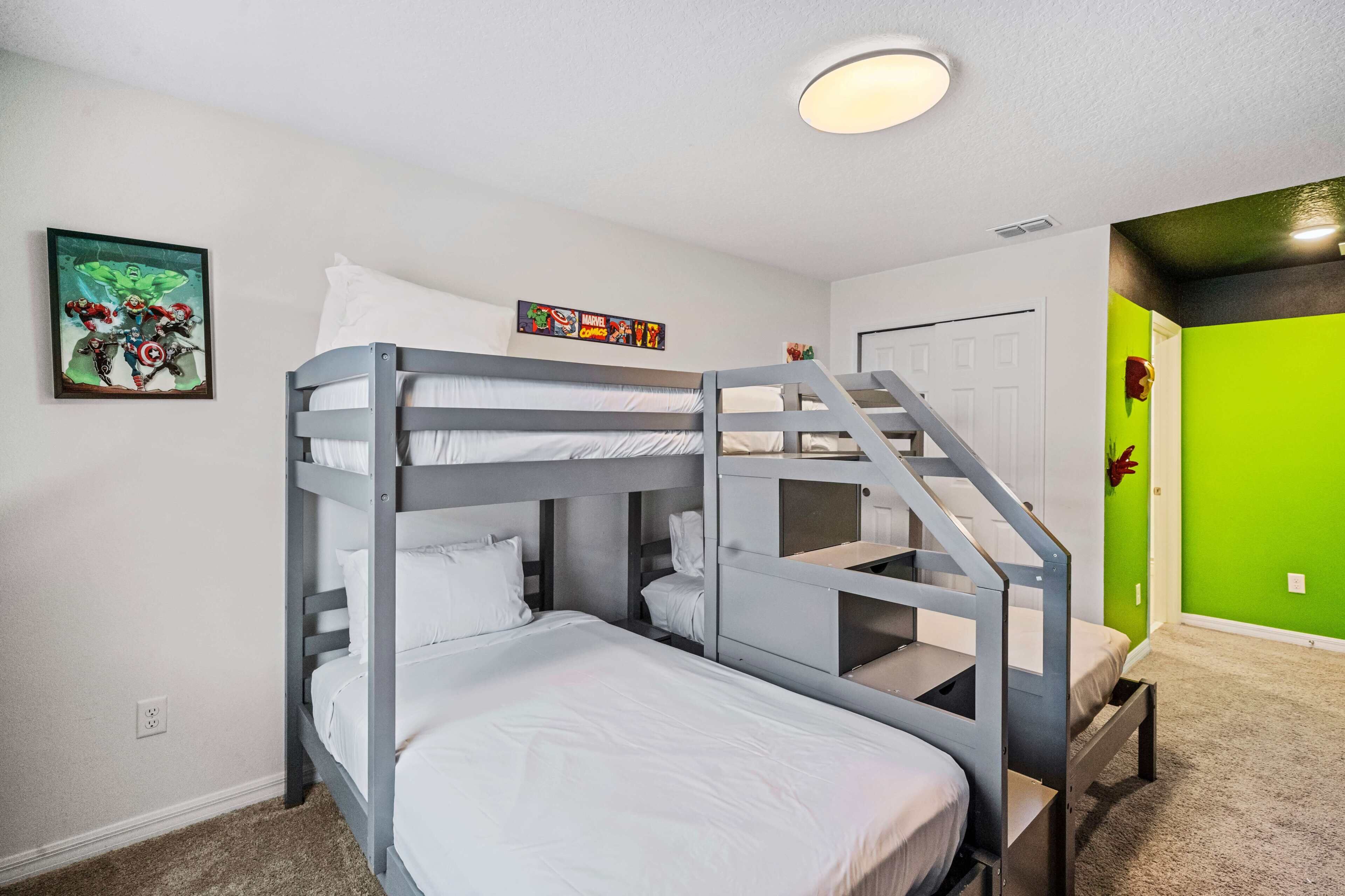 A bunk bed room with a staircase, a wall-mounted picture, and a green accent wall.
