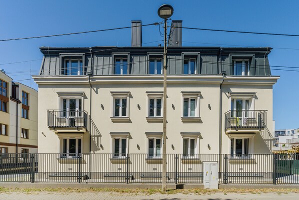 A multi-story building with balconies, a street lamp, and a fence. - ShortStayPoland Kazimierza Wielkiego (Warsaw)