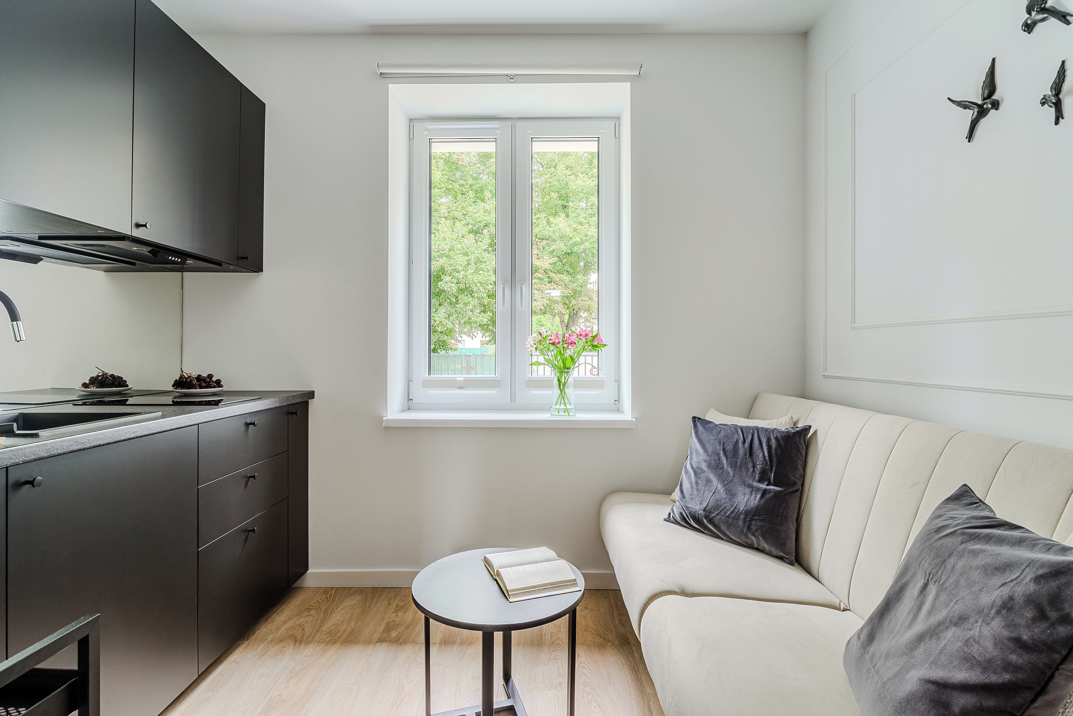 A modern kitchen with a window, a sofa, and a small table with a book.