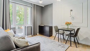 Una sala de estar moderna con un sofá, una mesa de comedor con sillas, un aparador negro y un aplique de pared.
