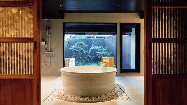 A modern bathroom with a large bathtub, wooden accents, and a view of a garden. - Kyoto Machiya Kamogawa Gardens (Kyoto)