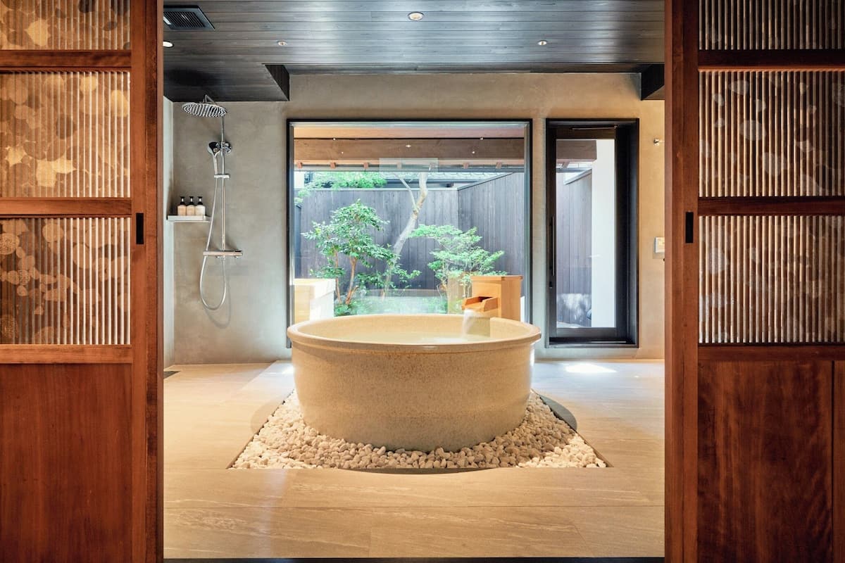 Een aparte badkuip en douche, een diep bad, een regendouche