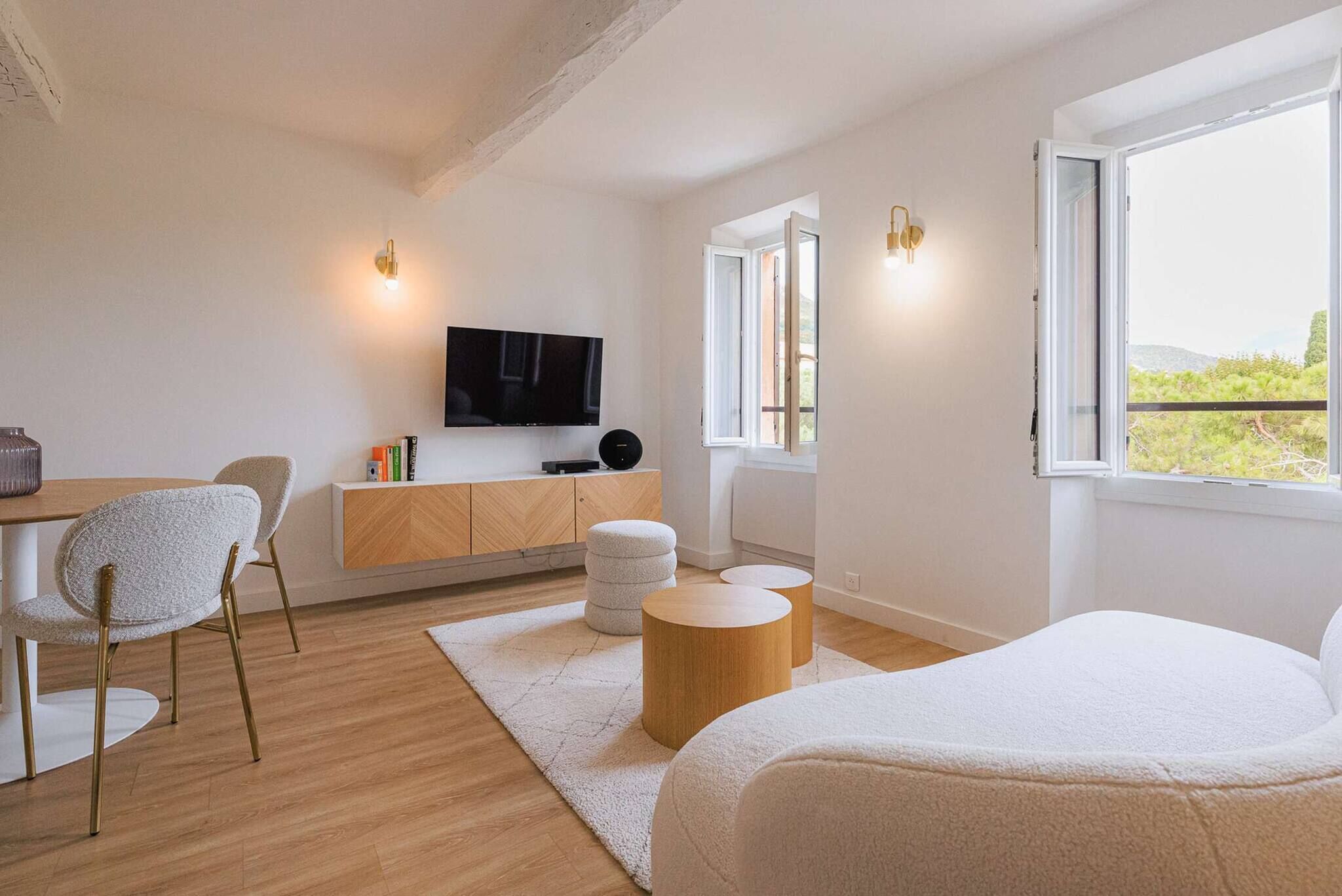 A modern bedroom with a bed, a desk, a TV, and a window with a view.
