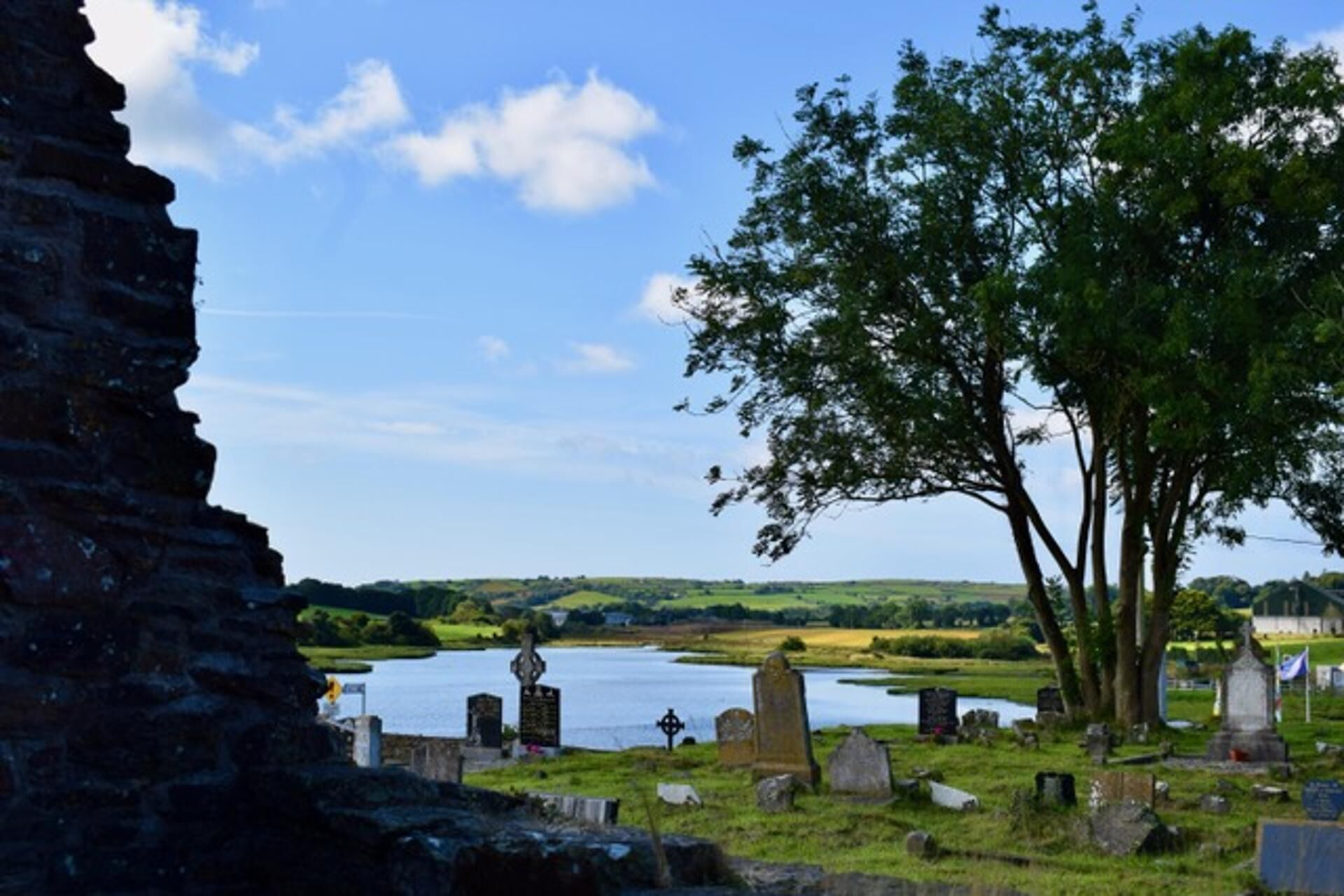 A cemetery with headstones and a body of water in the background.