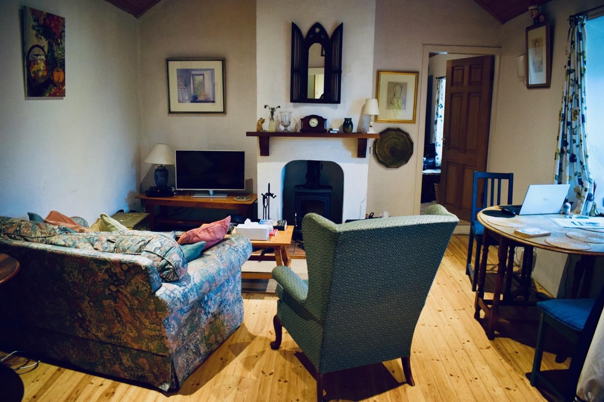 A living room with a sofa, armchair, TV, fireplace, and a dining area with a table and chairs.