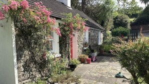 Een pad van stenen dat leidt naar een wit gebouw met roze bloeiende planten.