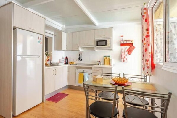 A compact kitchen with white cabinets, a microwave, and a dining area with a table and chairs.