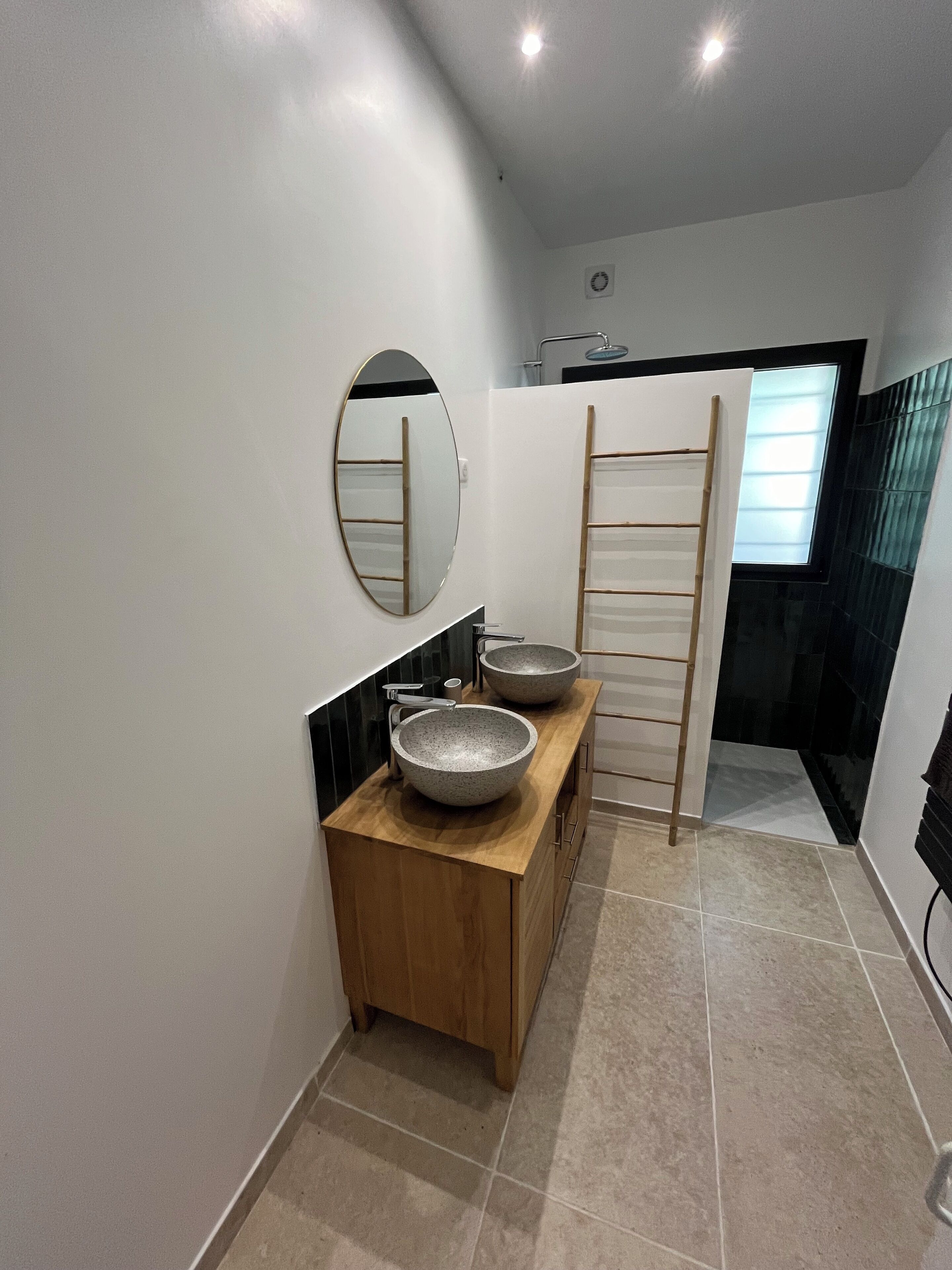 A modern bathroom with a wooden vanity, two large vessel sinks, a mirror, and a towel rack.
