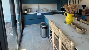 Une cuisine moderne avec des meubles bleus, un plan de travail blanc et un vase jaune.