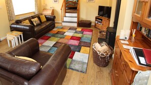 Un salón acogedor con un sofá de cuero marrón, una alfombra colorida, un mueble de madera y una chimenea.