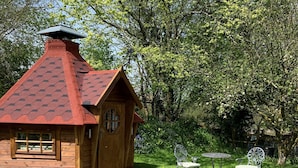 Una cabaña de madera con techo inclinado, un pequeño porche y una ventana.