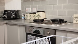 A kitchen with a gas stove, a toaster, and various kitchen items on the counter. - Entire Modern Home in Manchester For You (Manchester)