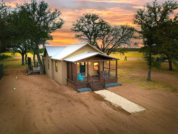 A small, single-story building with a porch and a covered outdoor seating area.