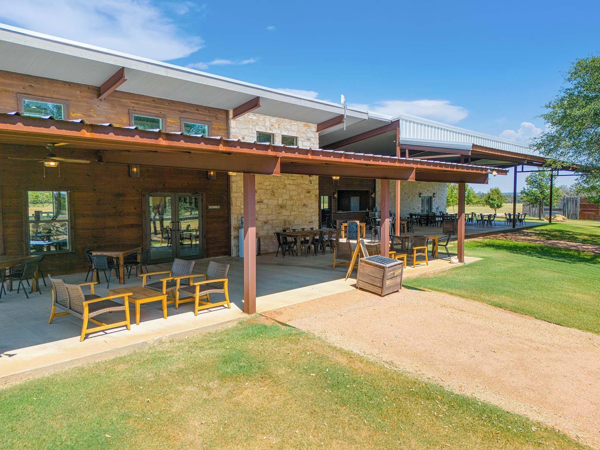 An outdoor patio area with tables and chairs, a covered seating area, and a stone building with windows.