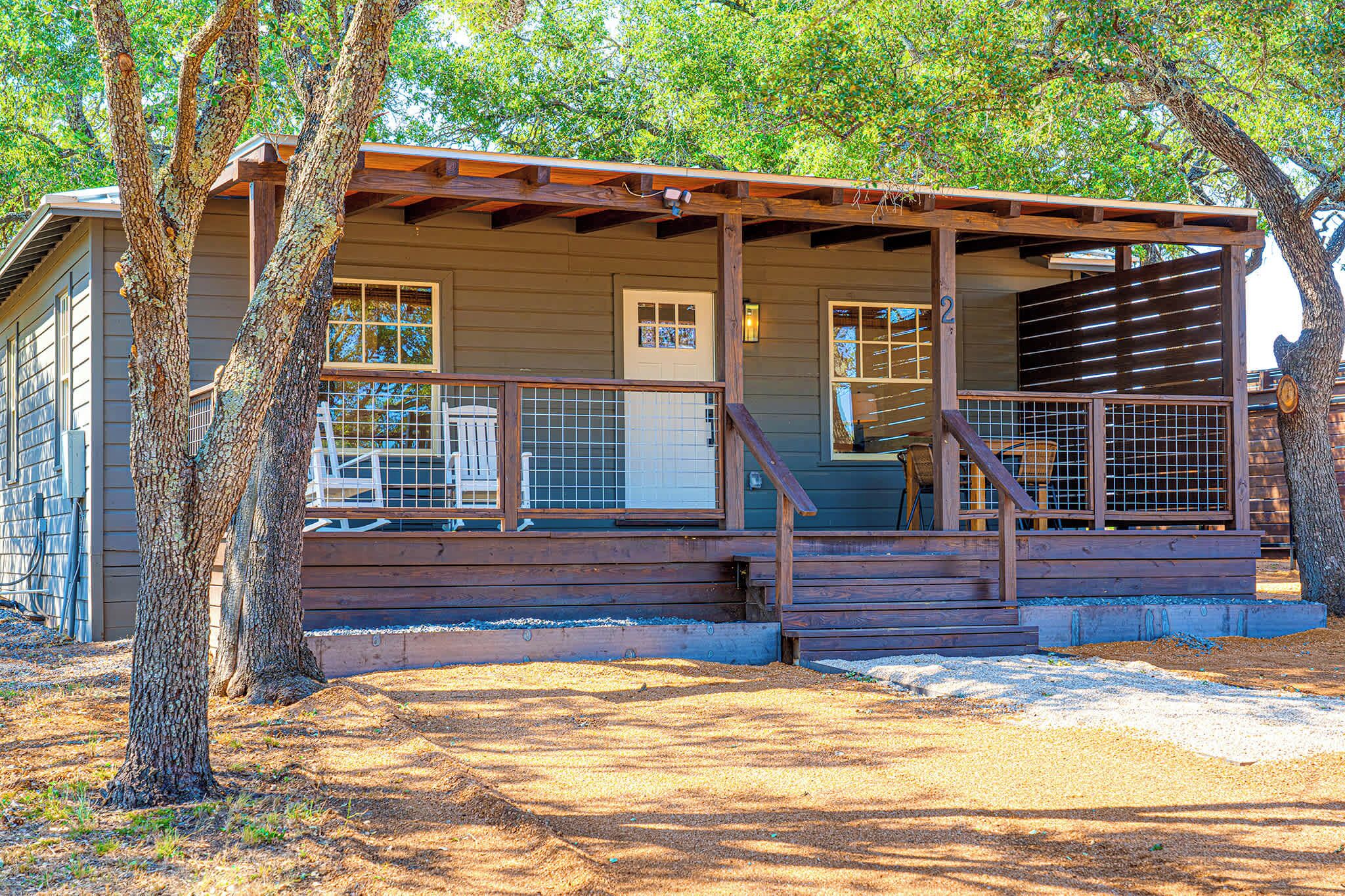 A wooden cabin with a porch, a door, and a window.