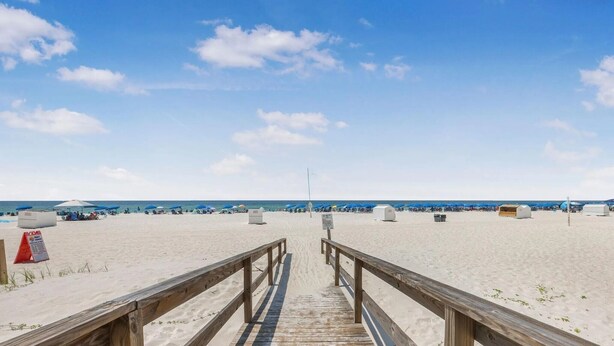 A wooden boardwalk leading to a sandy beach with umbrellas and beach huts. - Romar Lakes 103B (Orange Beach)