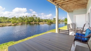 A covered deck with a view of a lake and trees. - Romar Lakes 103B (Orange Beach)
