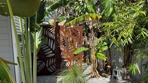 Un jardín con diversas plantas, una cerca decorativa y una pequeña mesa.