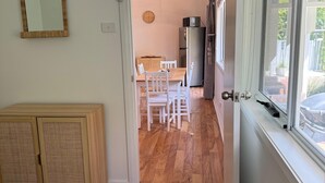 Una habitación con cama, un armario de madera, una mesa de comedor con sillas, un refrigerador y una ventana con vistas al exterior.