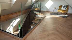 A modern loft with a glass staircase, wooden flooring, and a cozy seating area with a patterned cushion. - HOTEL NICE (Laupheim)