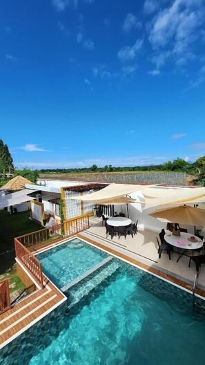 A rooftop pool area with a clear view of the surrounding landscape, including a distant field and trees. - Urban Glamp Resort Iloilo (Oton)