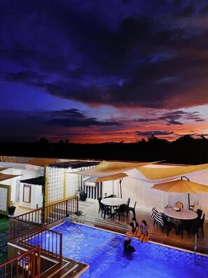 A pool area with umbrellas, a staircase, and a view of the sky at dusk. - Urban Glamp Resort Iloilo (Oton)