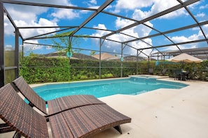 Un espace piscine extérieur abrité, doté de chaises longues et offrant une vue sur le paysage environnant.