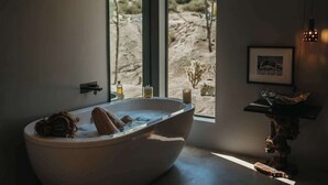 Un baño moderno con una bañera independiente, un ventanal con vistas al desierto y una decoración minimalista.