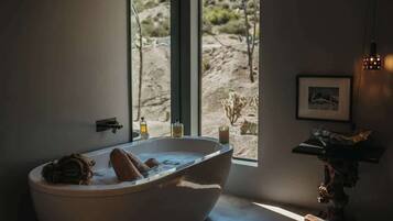 Un bagno moderno con una vasca da bagno indipendente, una finestra con vista sul deserto e un arredamento minimalista.