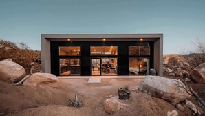 Un edificio moderno con amplios ventanales, techo plano y paisaje desértico.