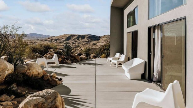 Eine moderne Außenpatio mit weißen Stühlen und Blick auf eine Wüstenlandschaft.